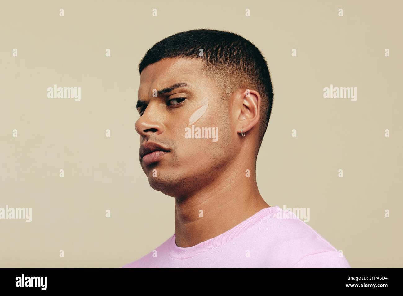 Ritratto di un giovane che si prende cura della sua pelle utilizzando un siero facciale, per ottenere idratazione e nutrimento. Giovane maschio mantenendo la sua bellezza con Foto Stock