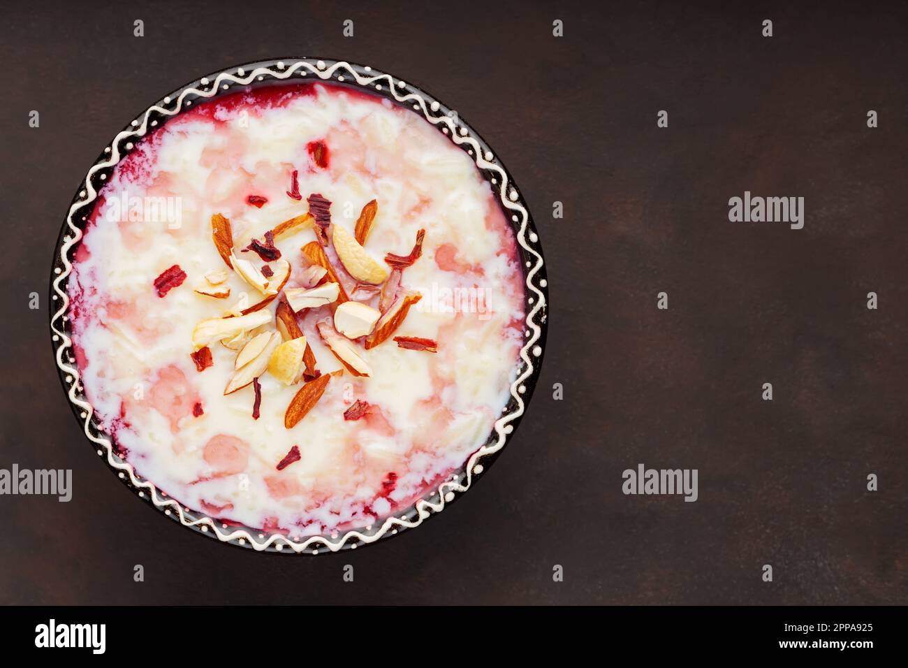 Budino di riso kheer indiano con noci su fondo scuro. Delizioso budino di riso con acqua di rosa. Spazio di copia. Vista dall'alto Foto Stock