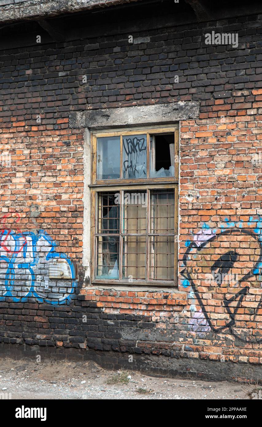 Finestra rotta su vecchio graffiti coperto edificio in mattoni rossi derelitti Foto Stock