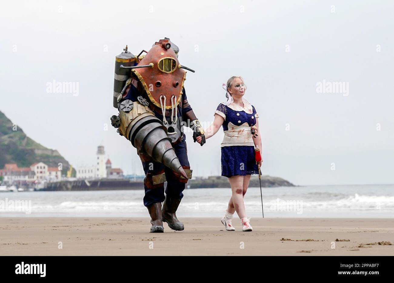 Bradley Calvert (a sinistra) e Georgina Donnalley (a destra) posano per una fotografia vestita come personaggi del videogioco in prima persona BioShock 2, mentre camminano lungo la spiaggia di Scarborough durante lo sci Fi Scarborough presso il complesso Spa di Scarborough. Data immagine: Domenica 23 aprile 2023. Foto Stock