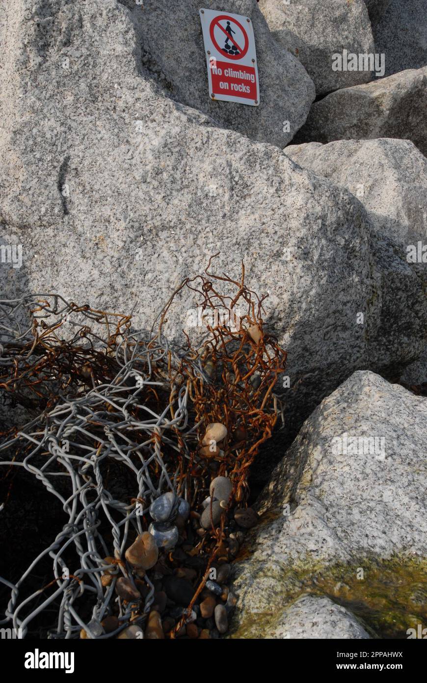Spezzati pezzi di gabione di filo alluvione difesa su 35 metri di roccia revment, con segno che dice che non salire sulle rocce. Spiaggia di Thorpeness. 15th febbraio 2023 Foto Stock