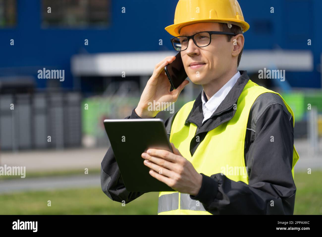 Logistico con telefono e tablet digitale sullo sfondo del centro logistico. Foto di alta qualità Foto Stock