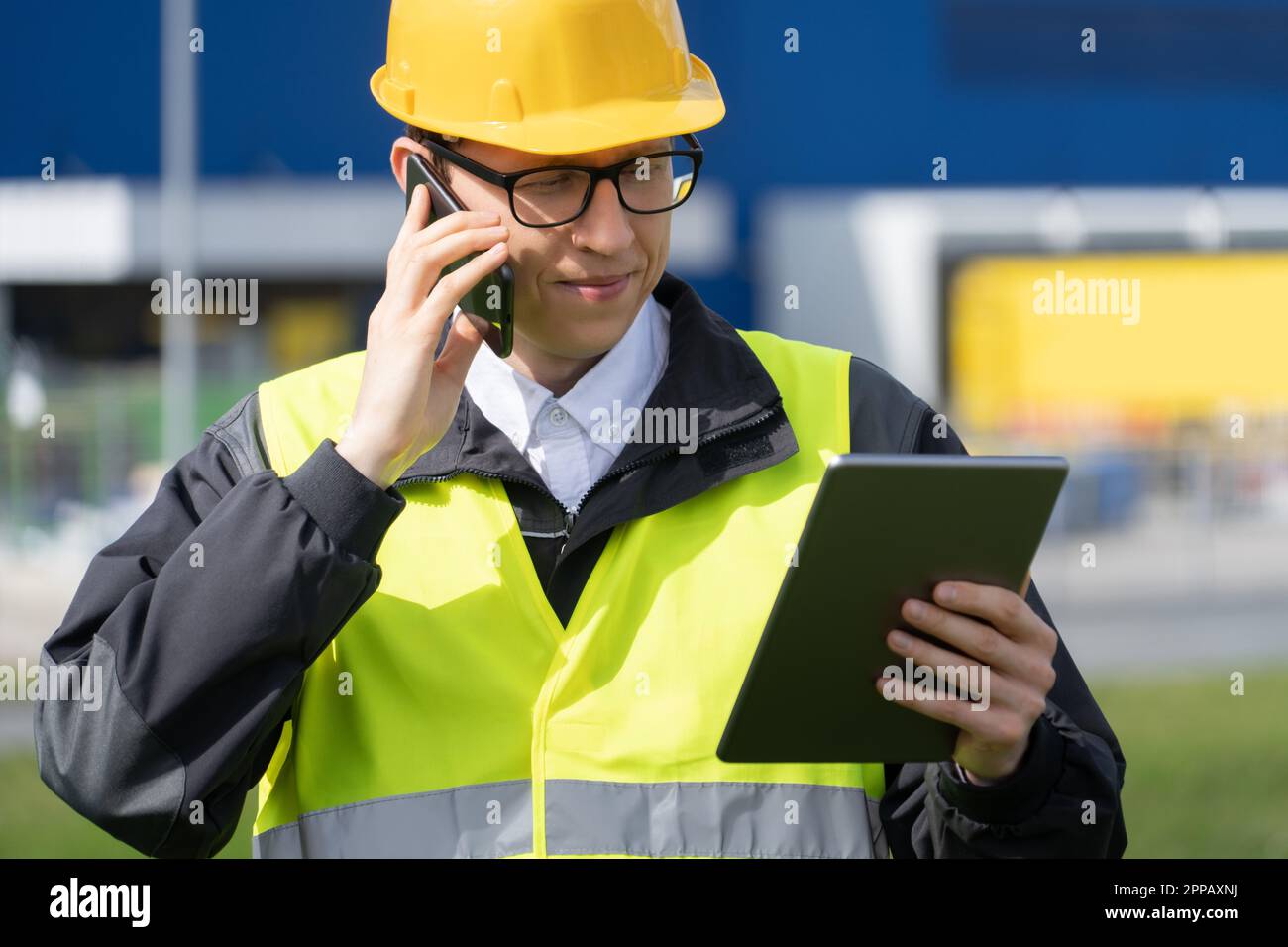 Logistico con telefono e tablet digitale sullo sfondo del centro logistico. Foto di alta qualità Foto Stock