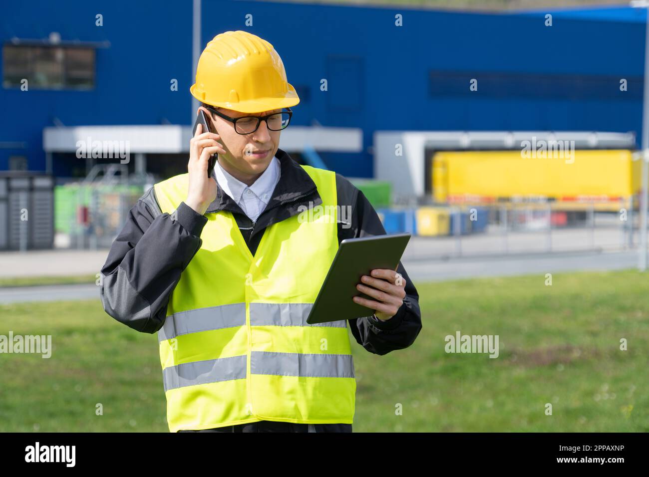 Logistico con telefono e tablet digitale sullo sfondo del centro logistico. Foto di alta qualità Foto Stock