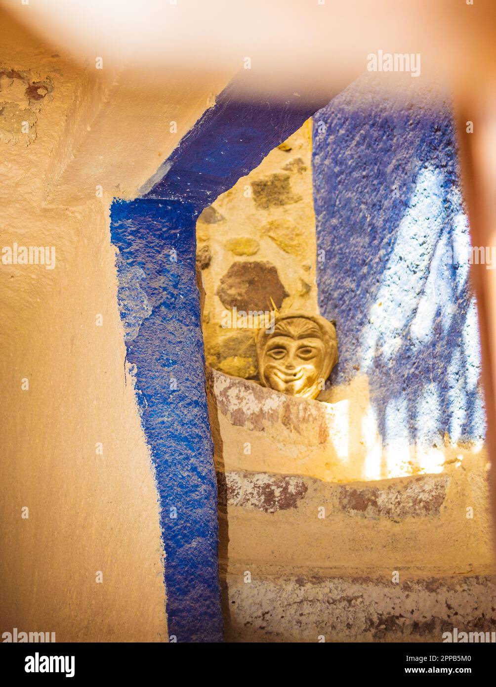 Vecchia maschera veneziana in argilla su una scala interna vista dalla finestra del Castello di Pyrgos Kallistis, Santorini, Grecia, Settembre 2013 Foto Stock
