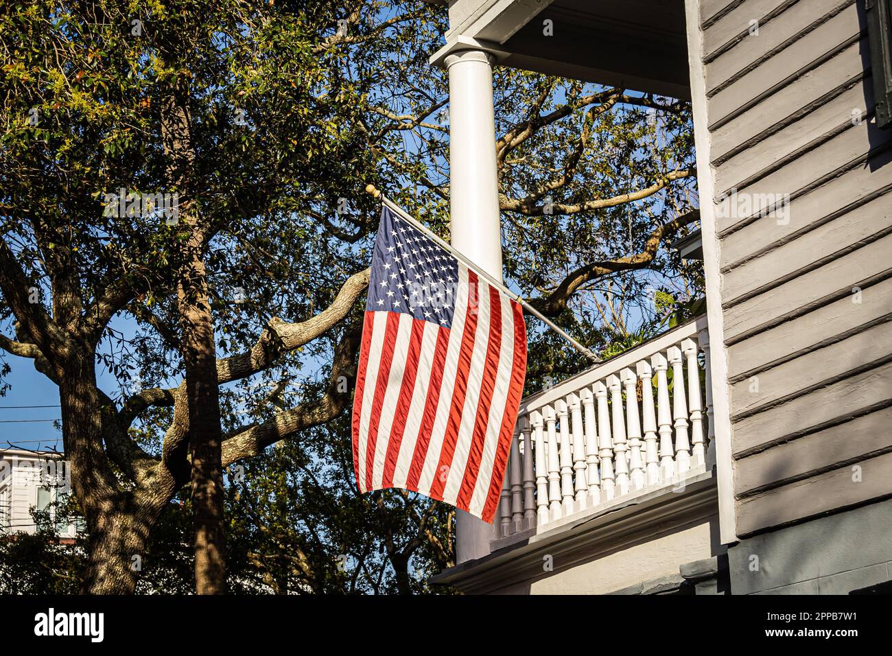 Un'esposizione patriottica di una bandiera americana appesa sul lato di una casa alla luce diretta del sole. Foto Stock