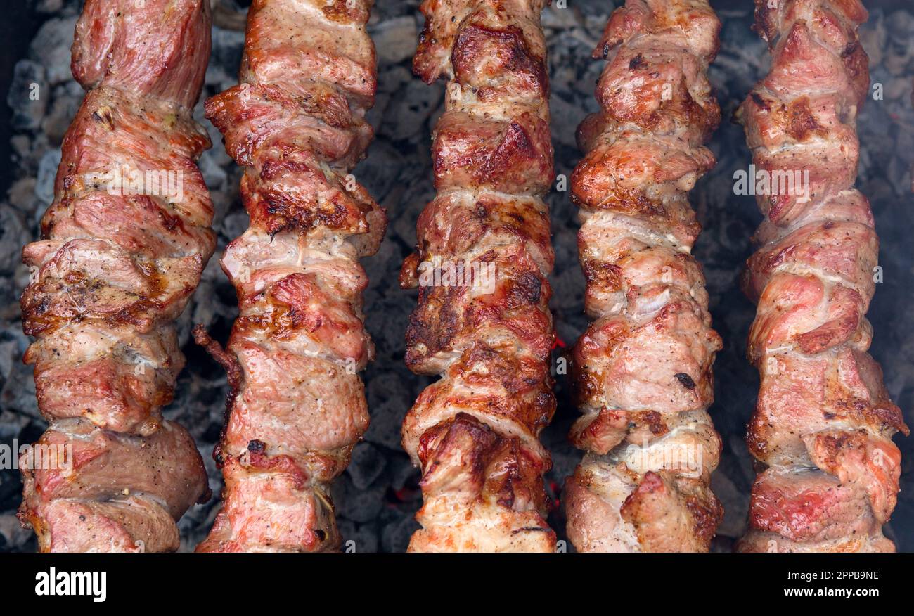 Barbecue di cottura su carbone. Shashlik o kebab shish preparato su carbone caldo. Pezzi di carne di maiale alla griglia su spiedini di metallo. Foto Stock
