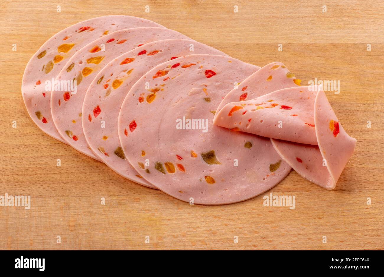 Fettine di salsiccia di paprika lyoner con peperone rosso, su tagliere di legno Foto Stock