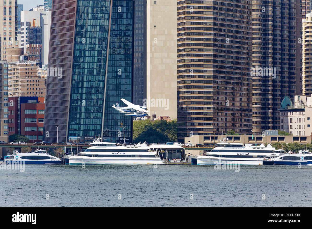 Il Tropic Oceans Airways Cessna 208B decade dalla base degli idrovolanti dello Skyports di New York sull'East River. Background: The Copper and Manhattan Place. Foto Stock