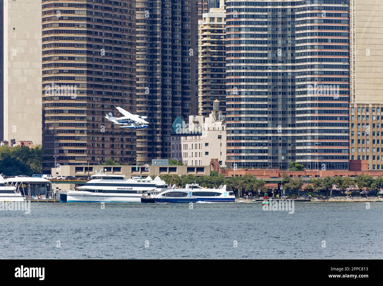 Il Tropic Oceans Airways Cessna 208B decade dalla base degli idrovolanti dello Skyports di NY. Background: Manhattan Place, i Condominium Corinzi e Horizon. Foto Stock