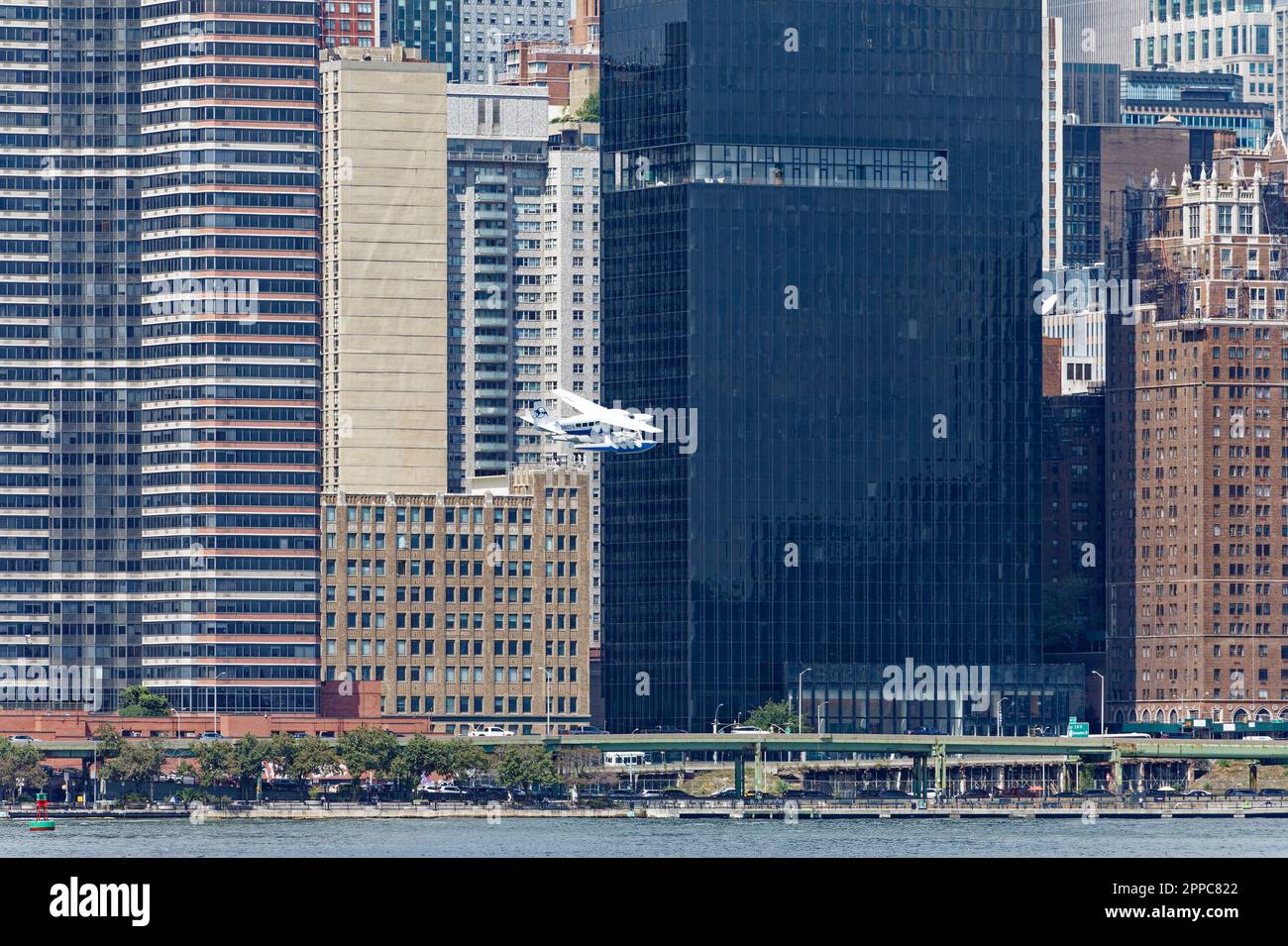 Il Tropic Oceans Airways Cessna 208B decade dalla base degli idrovolanti dello Skyports di New York sull'East River. Sfondo: 685 First Avenue Foto Stock