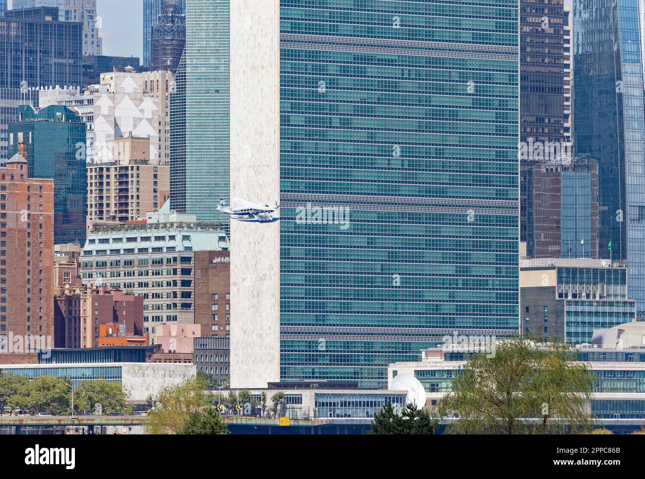 Il Tropic Oceans Airways Cessna 208B decade dalla base degli idrovolanti dello Skyports di New York sull'East River. Contesto: Edificio del Segretariato delle Nazioni Unite. Foto Stock