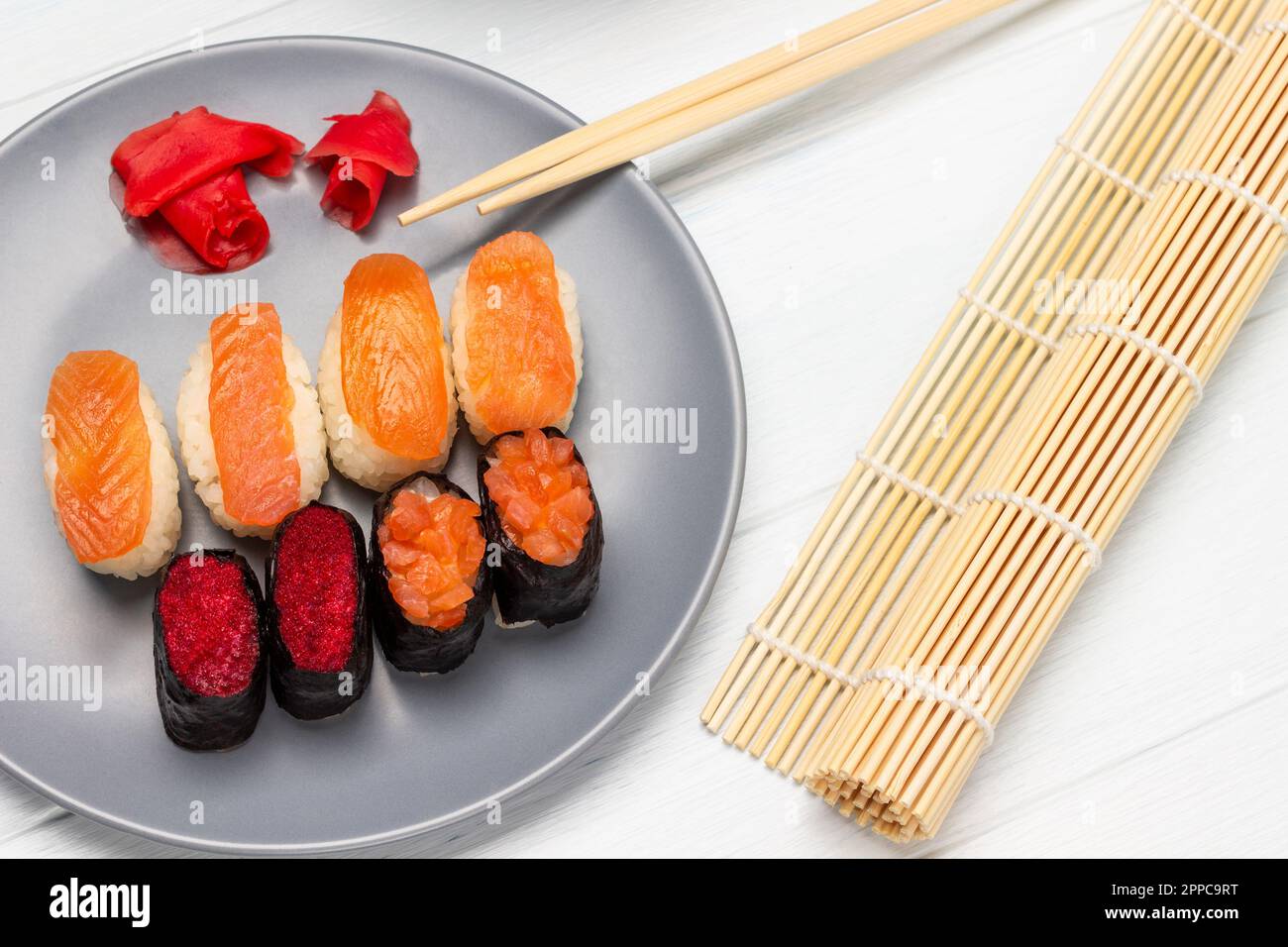 Sushi con salmone e caviale, zenzero rosa su piatto. Mensole e stuoia di  sushi di bambù. Giacitura piatta. Sfondo bianco Foto stock - Alamy