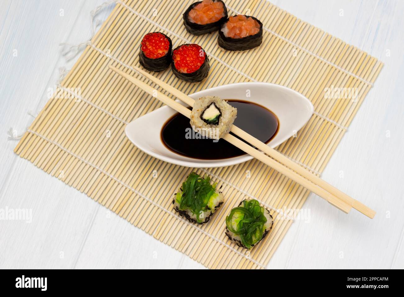 Sushi e bacchette su ciotola con salsa di soia. Sushi con caviale e alghe. Giacitura piatta. Sfondo bianco. Foto Stock