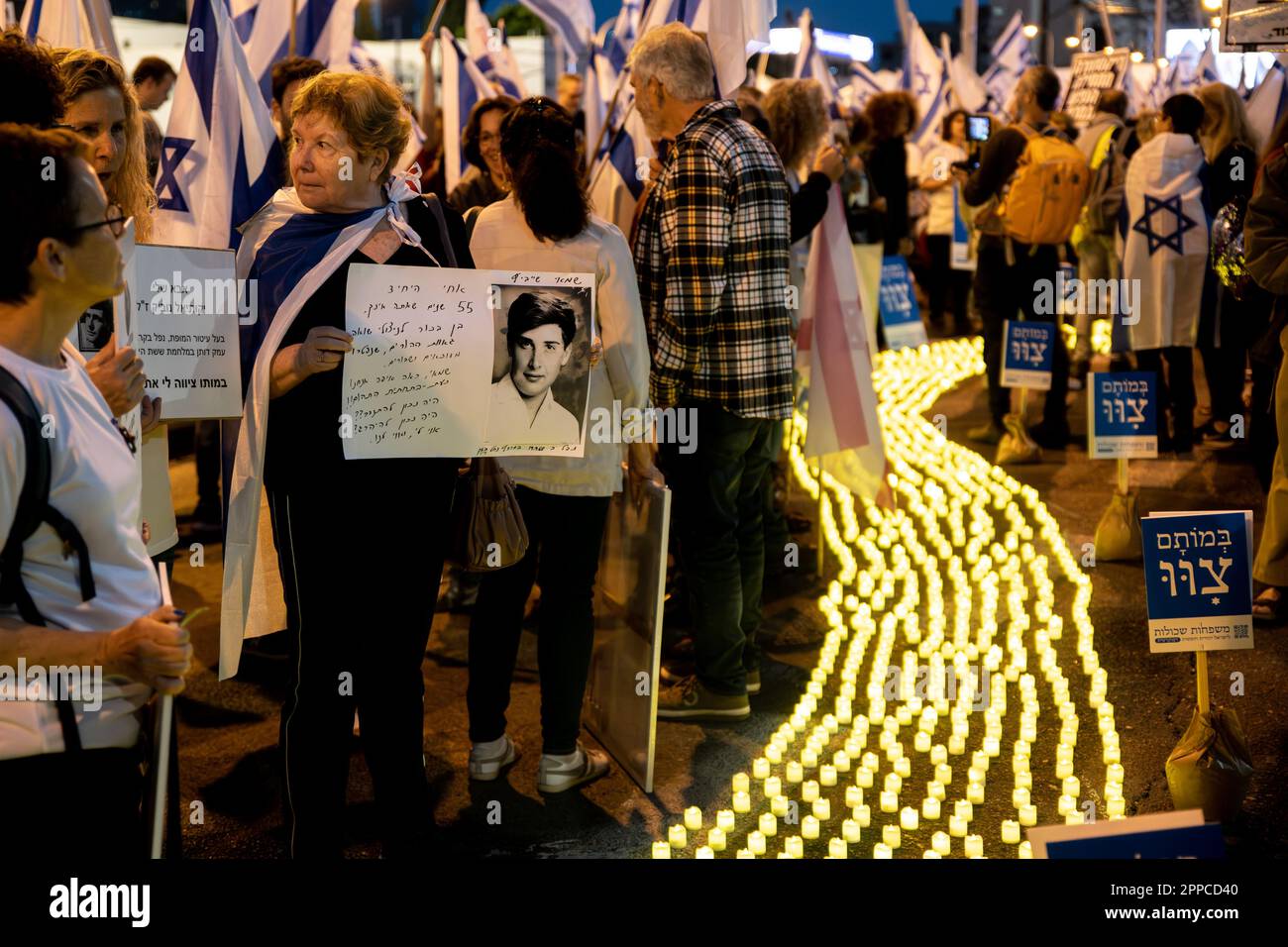 Israele. 22nd Apr, 2023. I membri della famiglia in lutto tengono una foto dei loro cari accanto a migliaia di candele “Yom HaZikaron” per la Giornata commemorativa dei soldati caduti israeliani e delle vittime degli attacchi terroristici durante una protesta contro la revisione giudiziaria a Tel Aviv. Apr 22th 2023. (Matan Golan/Sipa USA). Credit: Sipa USA/Alamy Live News Foto Stock