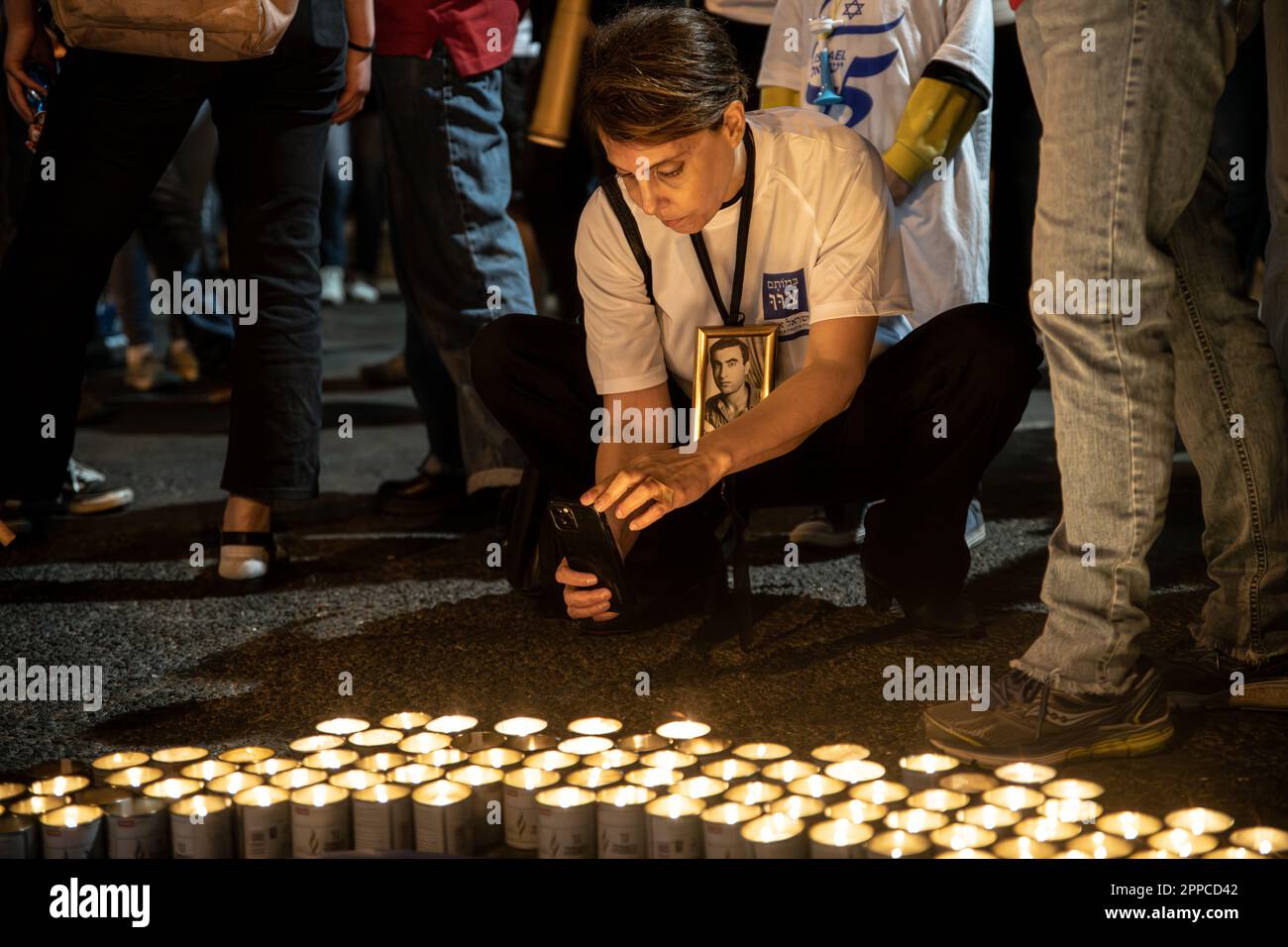 Israele. 22nd Apr, 2023. Un membro della famiglia perquisito porta con sé una foto della sua amata accanto a migliaia di candele “Yom HaZikaron” per la Giornata commemorativa dei soldati caduti israeliani e delle vittime degli attacchi terroristici durante una protesta contro la revisione giudiziaria a Tel Aviv. Apr 22th 2023. (Matan Golan/Sipa USA). Credit: Sipa USA/Alamy Live News Foto Stock