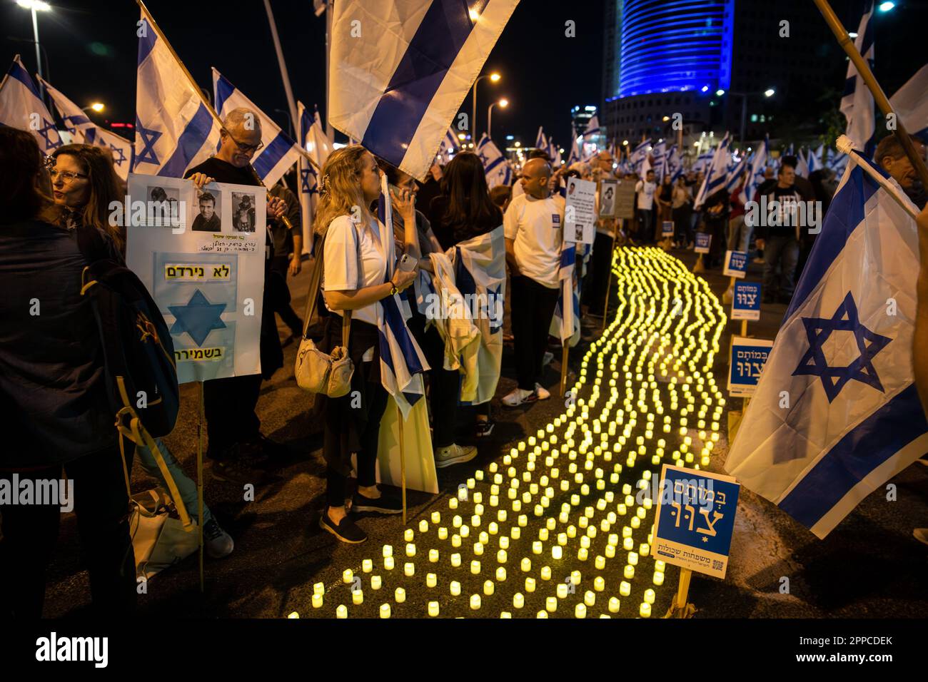 Israele. 22nd Apr, 2023. I membri della famiglia in lutto tengono una foto dei loro cari accanto a migliaia di candele “Yom HaZikaron” per la Giornata commemorativa dei soldati caduti israeliani e delle vittime degli attacchi terroristici durante una protesta contro la revisione giudiziaria a Tel Aviv. Apr 22th 2023. (Matan Golan/Sipa USA). Credit: Sipa USA/Alamy Live News Foto Stock