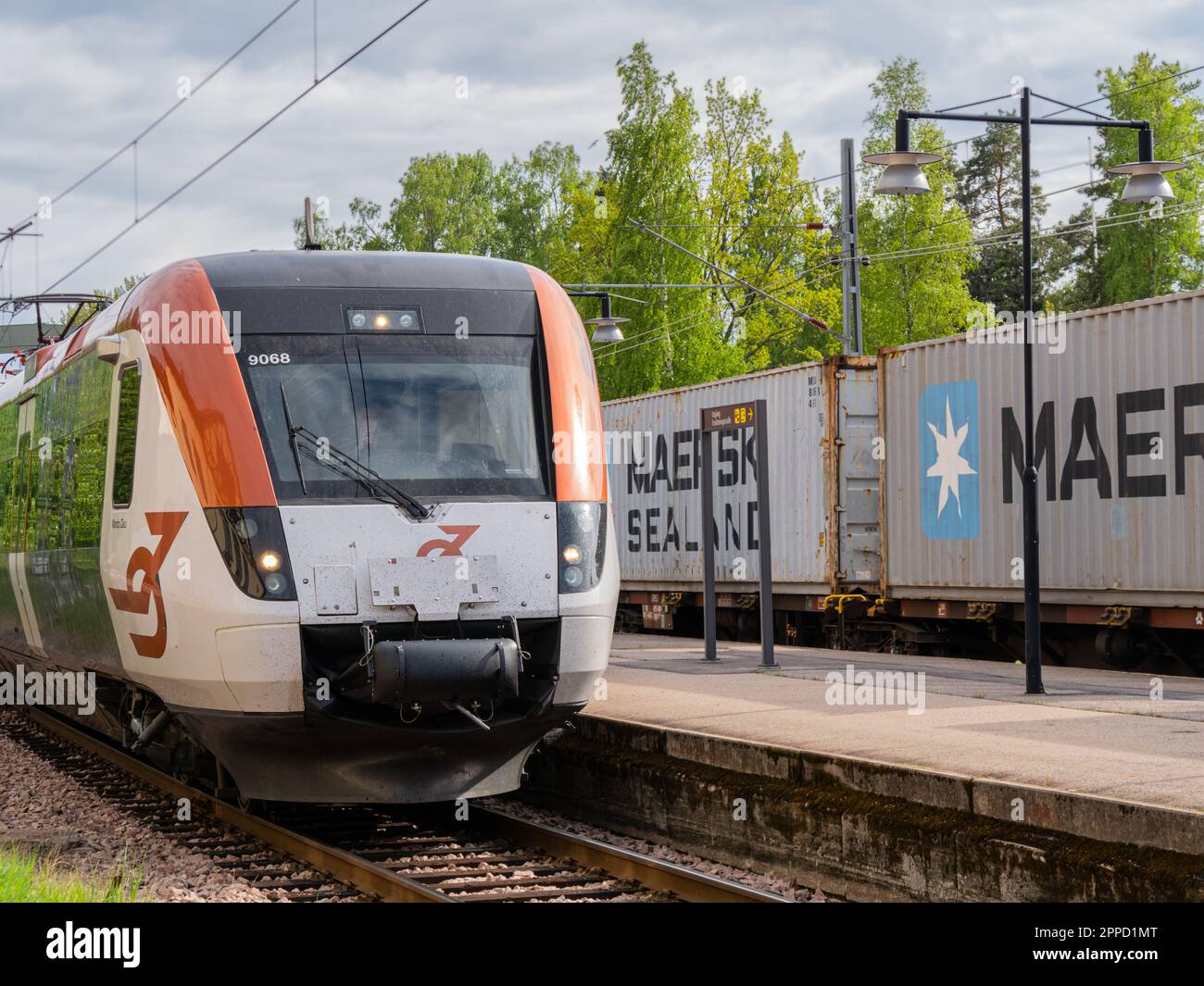 Angelsberg, Svezia - 28 maggio 2022: Un treno ferroviario che attraversa la campagna, una locomotiva è in contrasto con il cielo nuvoloso sopra. Trasporti pubblici Foto Stock