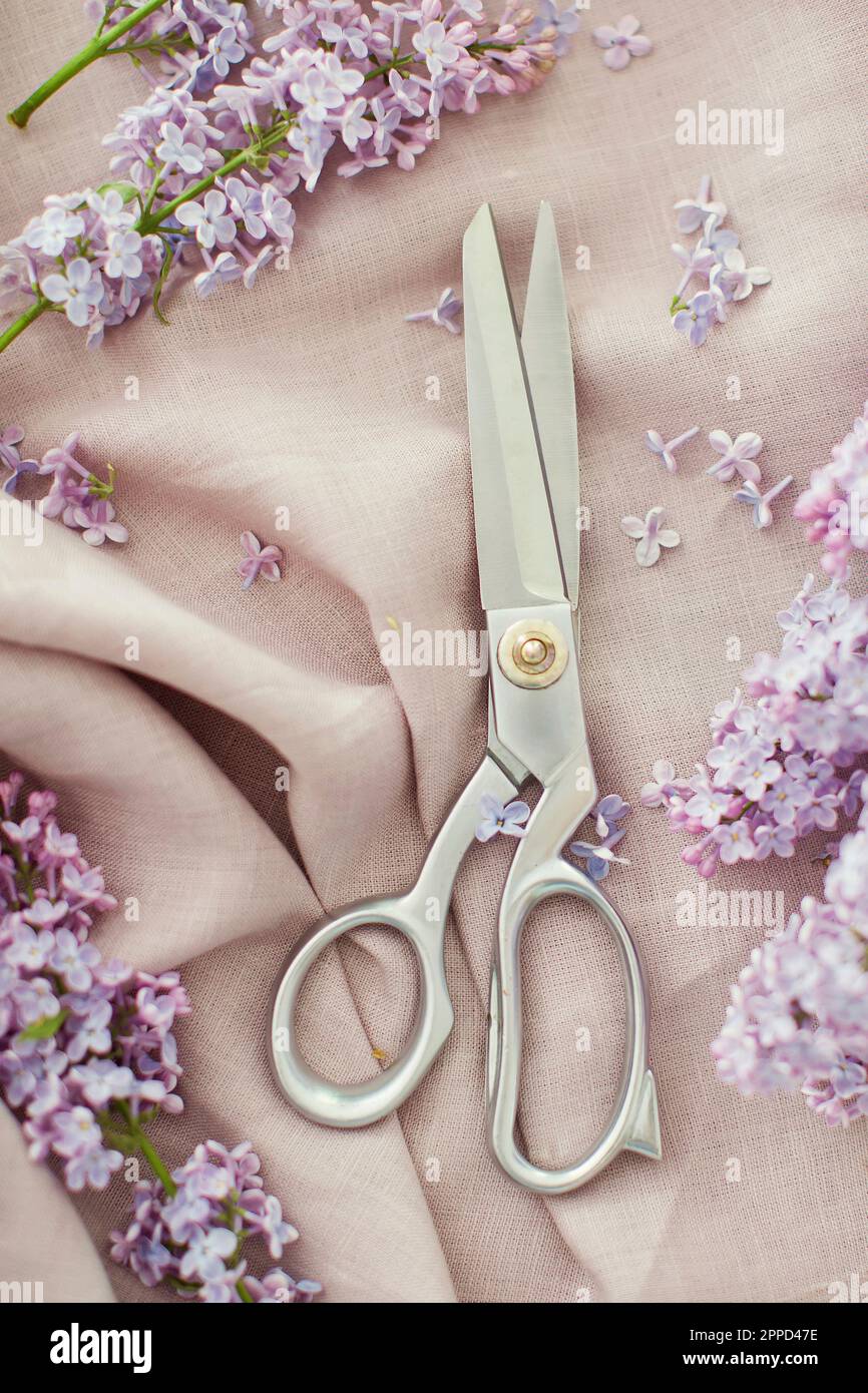 Forbici e fiori di lilla su tessuto di lino Foto Stock