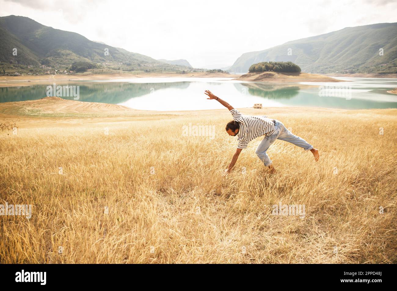 Uomo che fa la ruota di fronte al lago Foto Stock