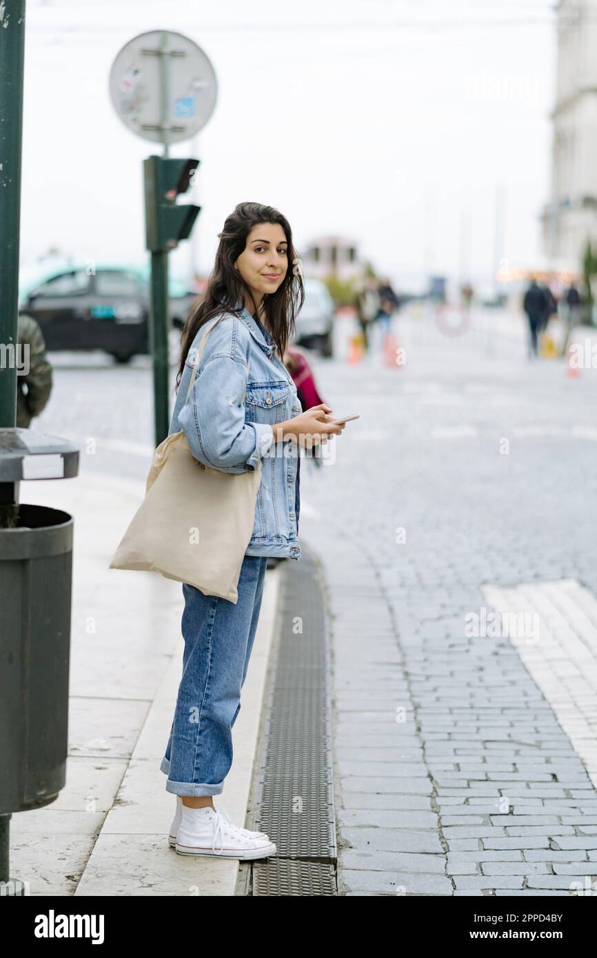 Donna sorridente con borsa tote in piedi sul sentiero Foto Stock