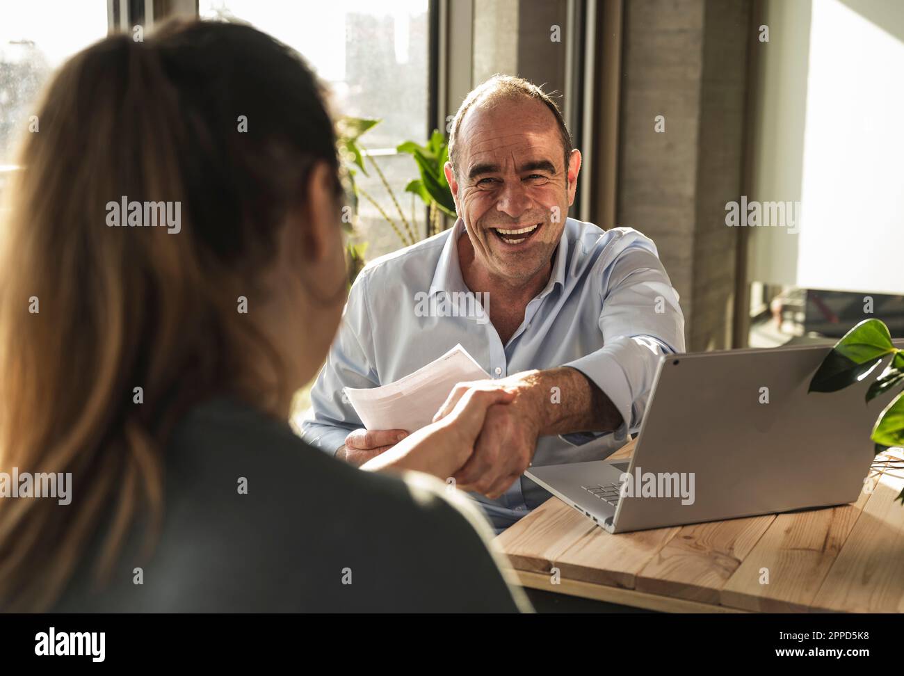Buon uomo d'affari maturo che fa la stretta di mano con il collega in ufficio Foto Stock