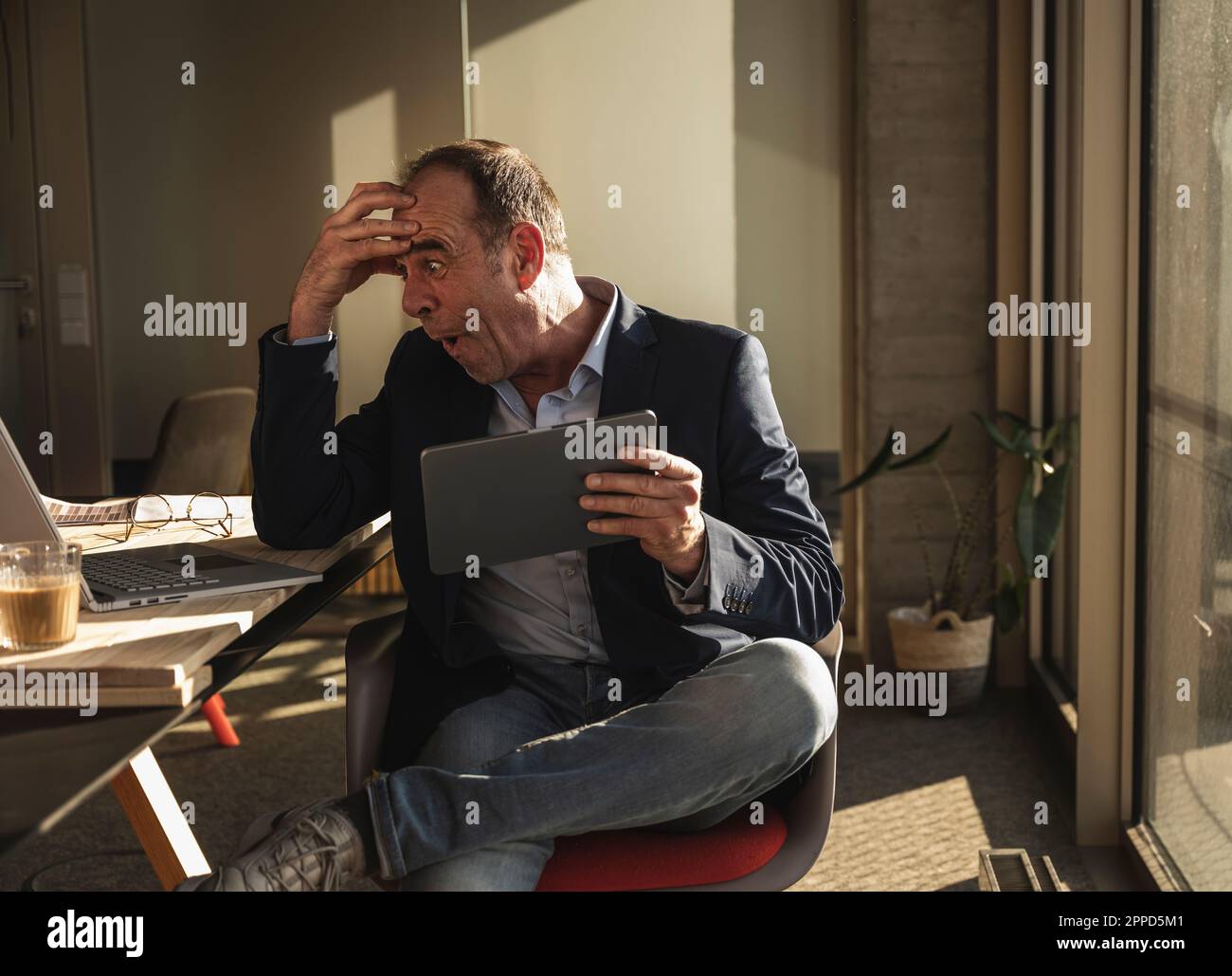 Scioccato uomo d'affari con la testa in mano guardando il notebook in ufficio Foto Stock