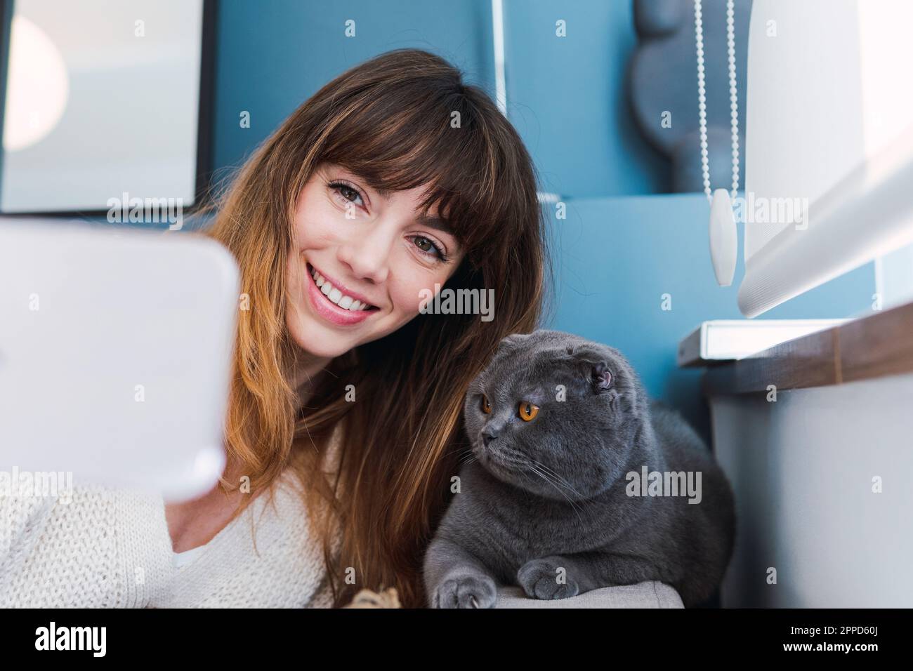 Donna felice che prende selfie con gatto a casa Foto Stock