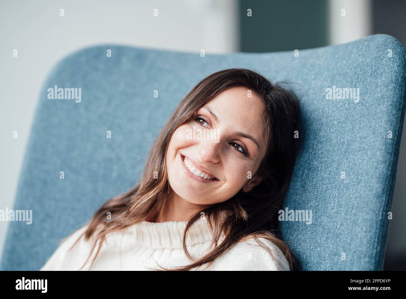 Donna felice e premurosa che riposa in poltrona Foto Stock