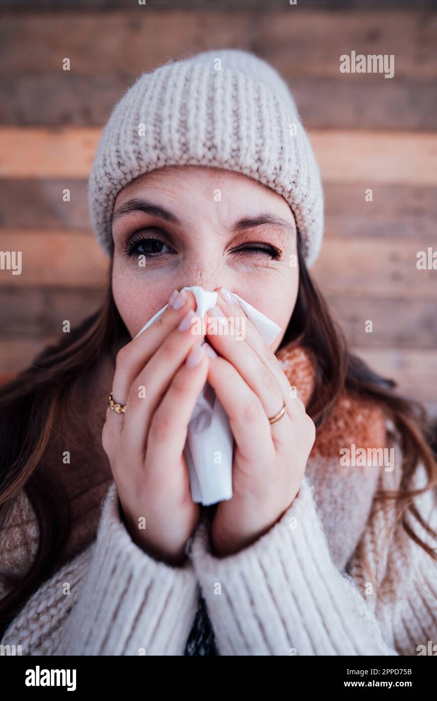 Giovane donna malata che asciuga il naso con il tessuto Foto Stock