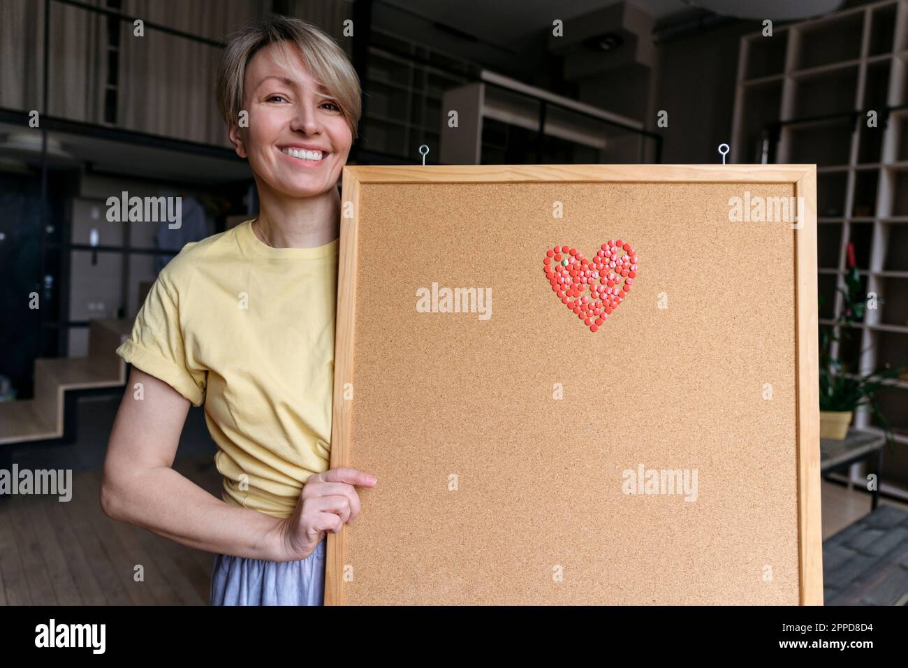 Donna felice che mostra il bordo del bollettino con il cuore emoji Foto Stock
