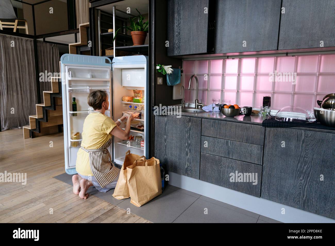 Donna che immagazzina generi alimentari in frigorifero a casa Foto Stock