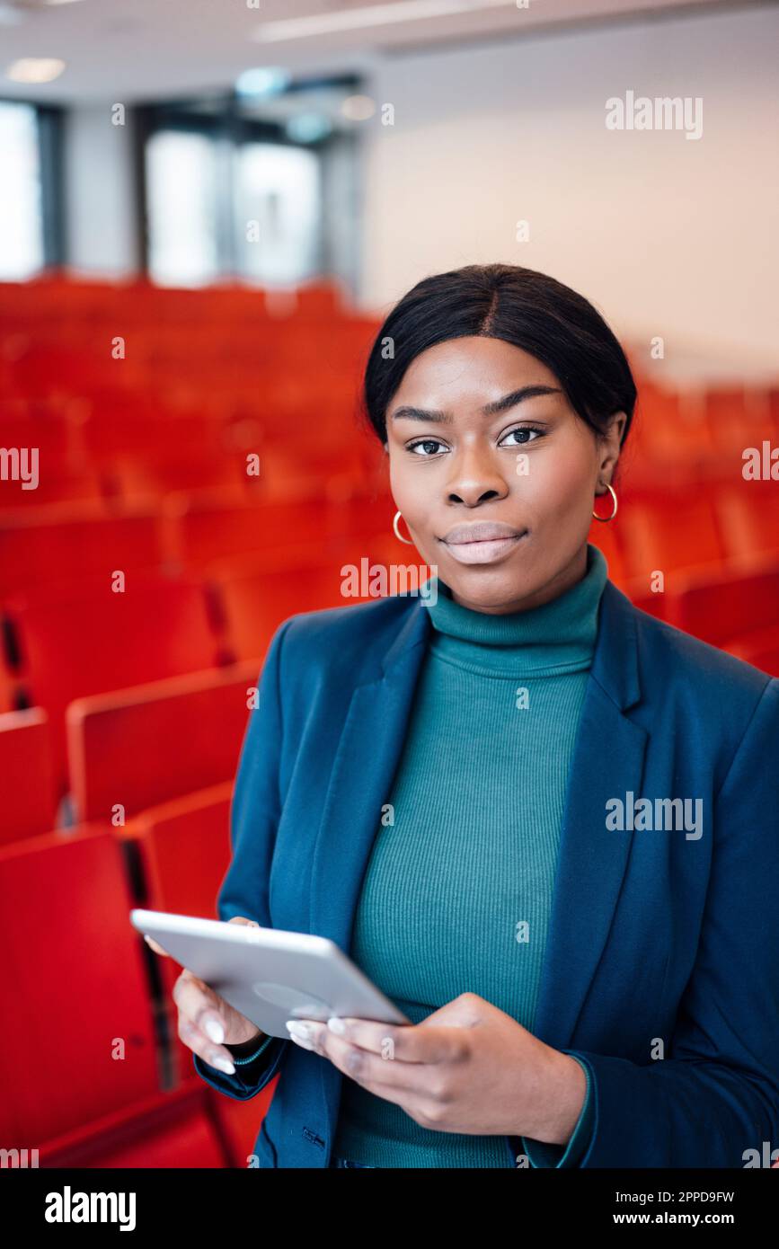 Giovane donna sicura con un tablet PC in auditorium Foto Stock