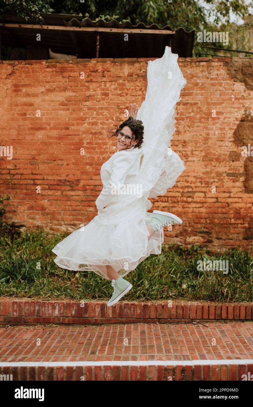 Donna felice nel vestito di nozze che salta sul sentiero Foto Stock