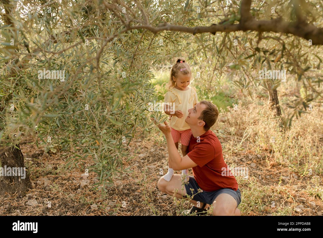 Sorridente padre che mostra olive a figlia in giardino Foto Stock