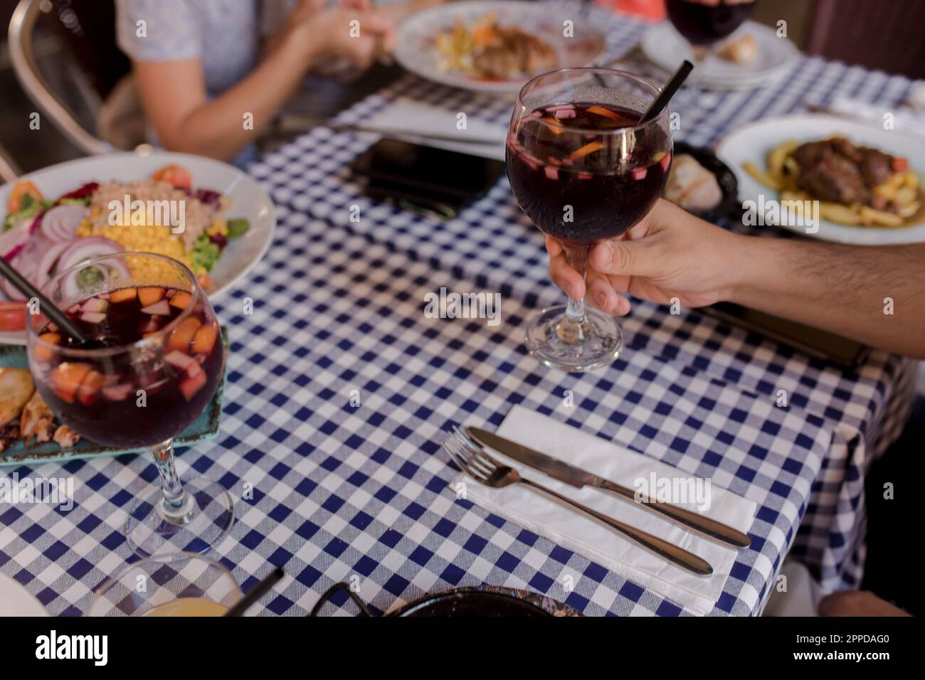 Mano dell'uomo che tiene un bicchiere di sangria Foto Stock