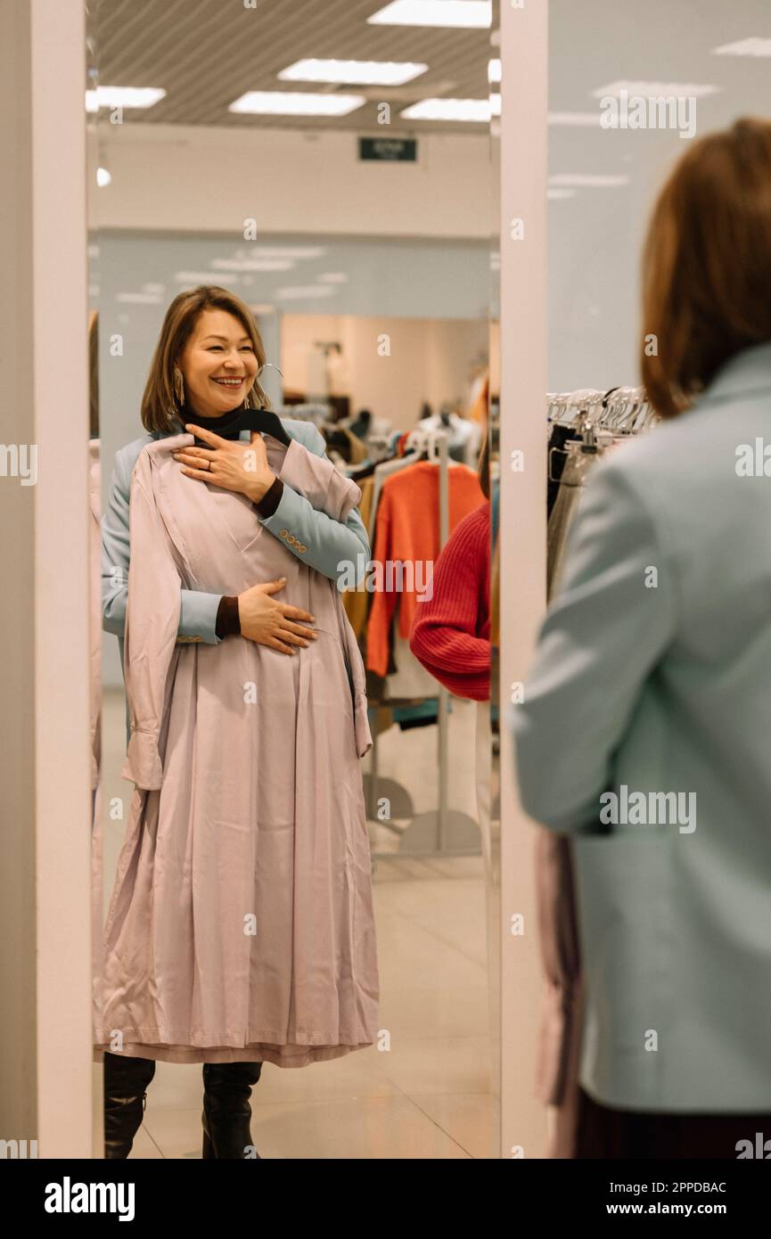 Donna felice con vestito che guarda nello specchio Foto Stock