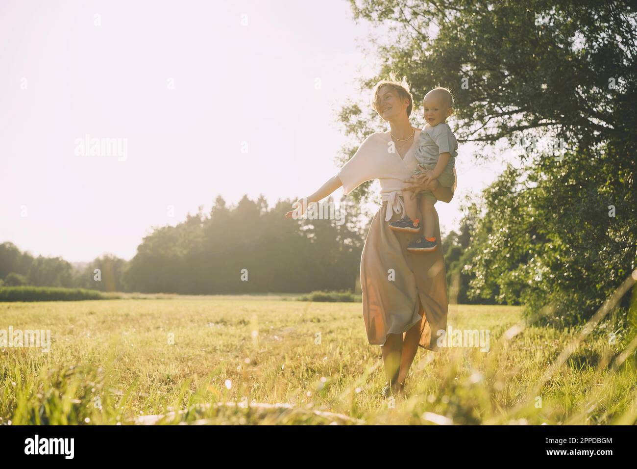 Madre allegra che porta il figlio e cammina nella natura Foto Stock