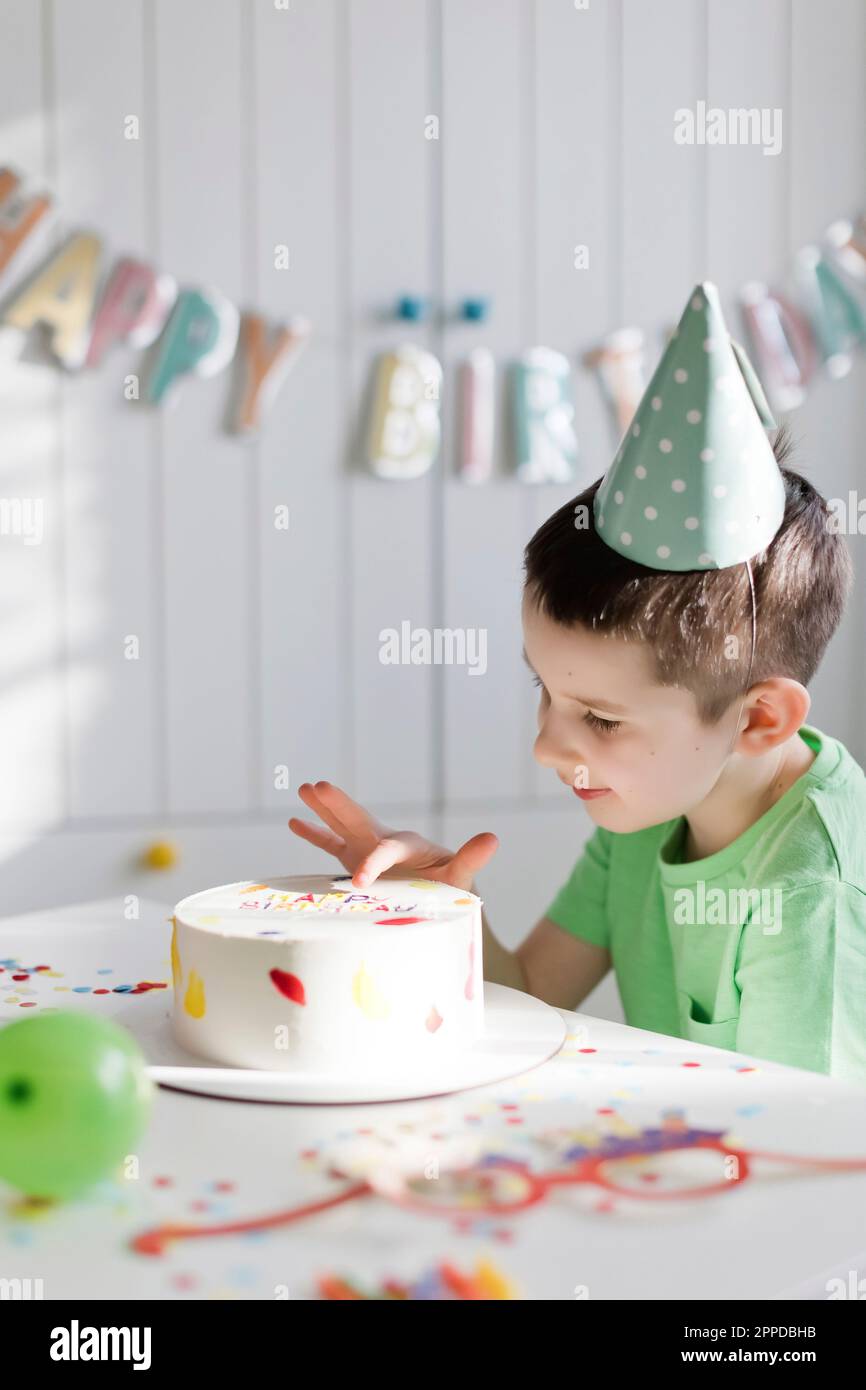 Ragazzo toccare torta di compleanno sul tavolo a casa Foto Stock