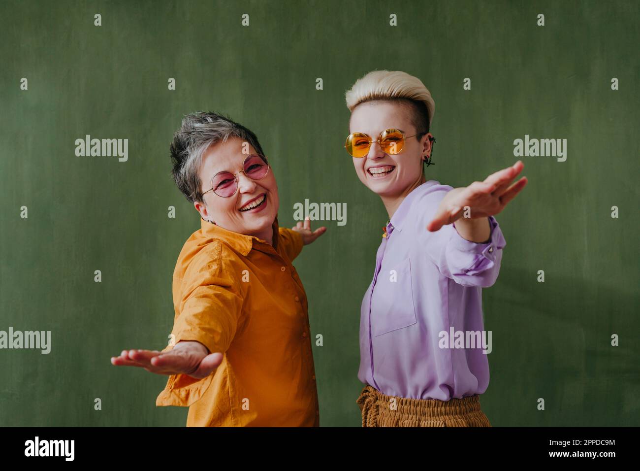 Spensierata madre e figlia che si divertono davanti al muro verde Foto Stock