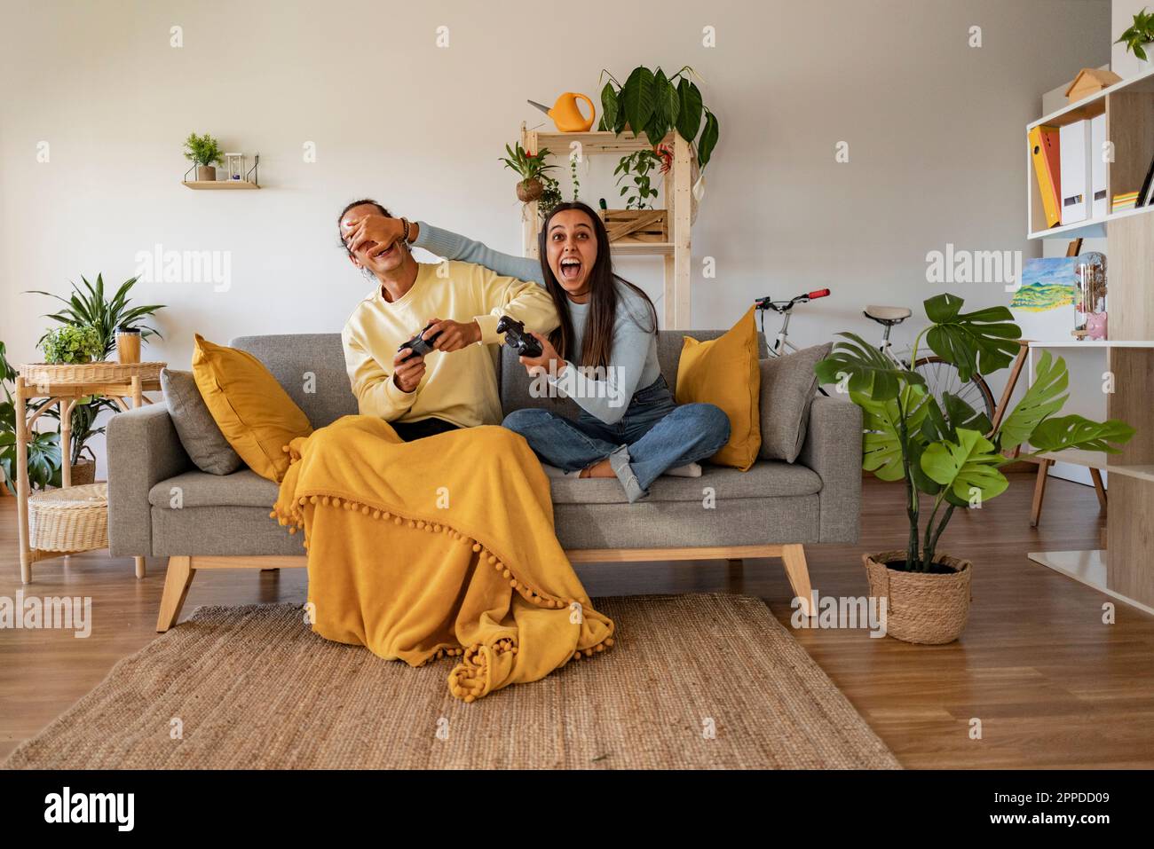 Coppia che si diverti a guardare un videogioco nel salotto di casa Foto Stock