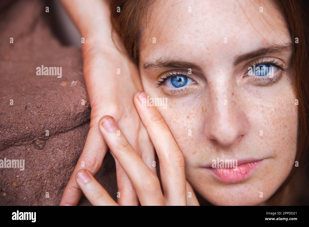 Giovane donna con occhi blu appoggiati sulla roccia Foto Stock