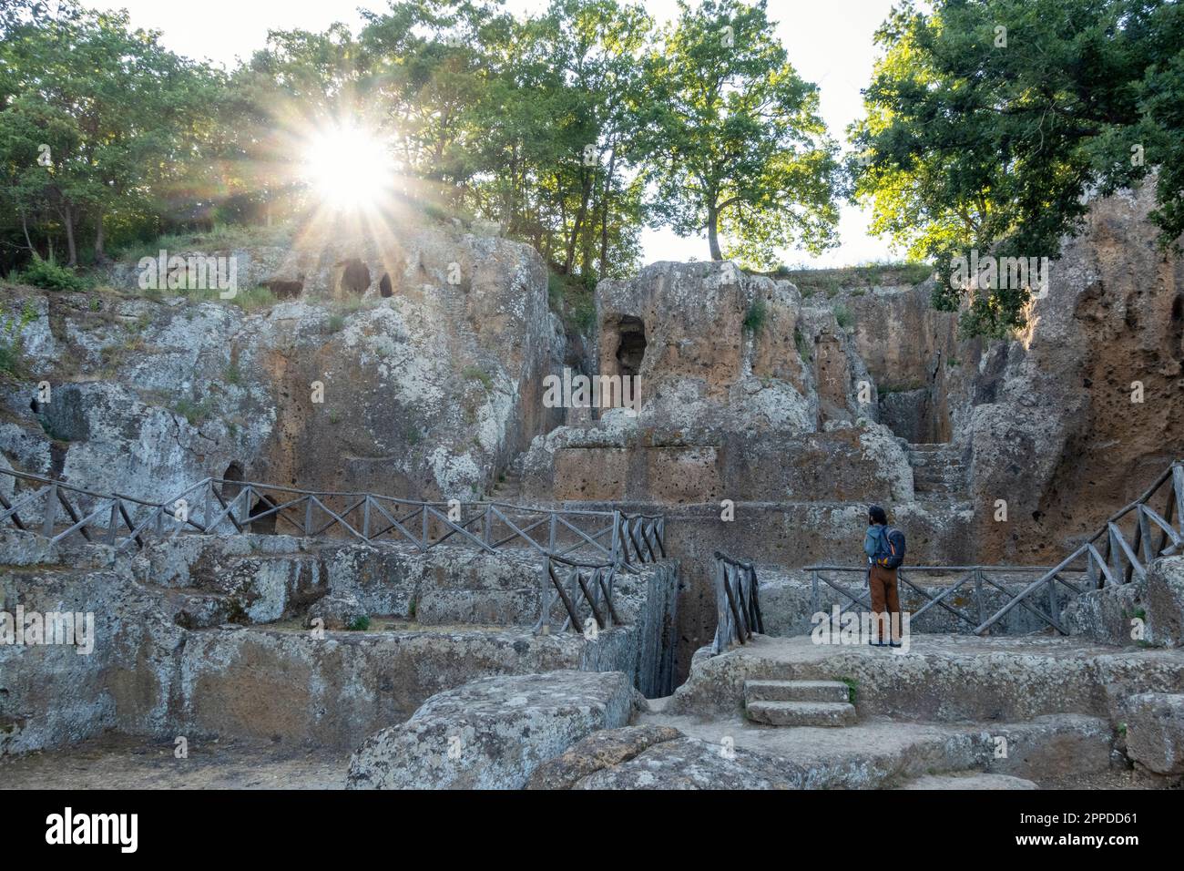 Uomo che indossa uno zaino che guarda la tomba del tempio di pietra, Toscana, Italia Foto Stock