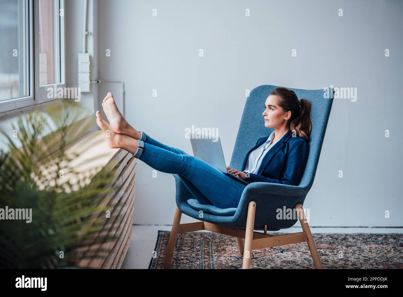 Donna d'affari premurosa seduta su poltrona con computer portatile Foto Stock