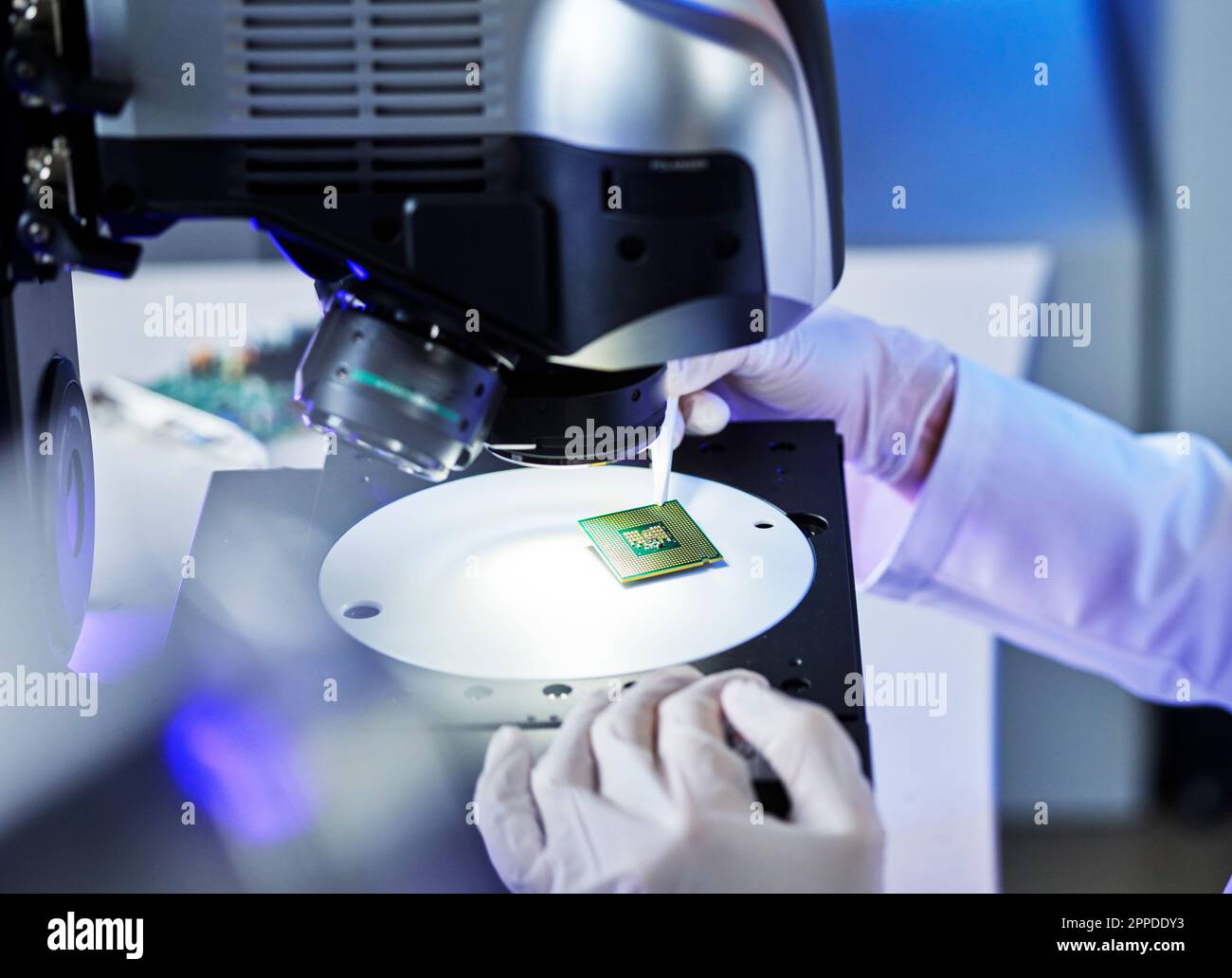 Mani di un tecnico che esamina i chip elettrici al microscopio presso e-Laboratory Foto Stock