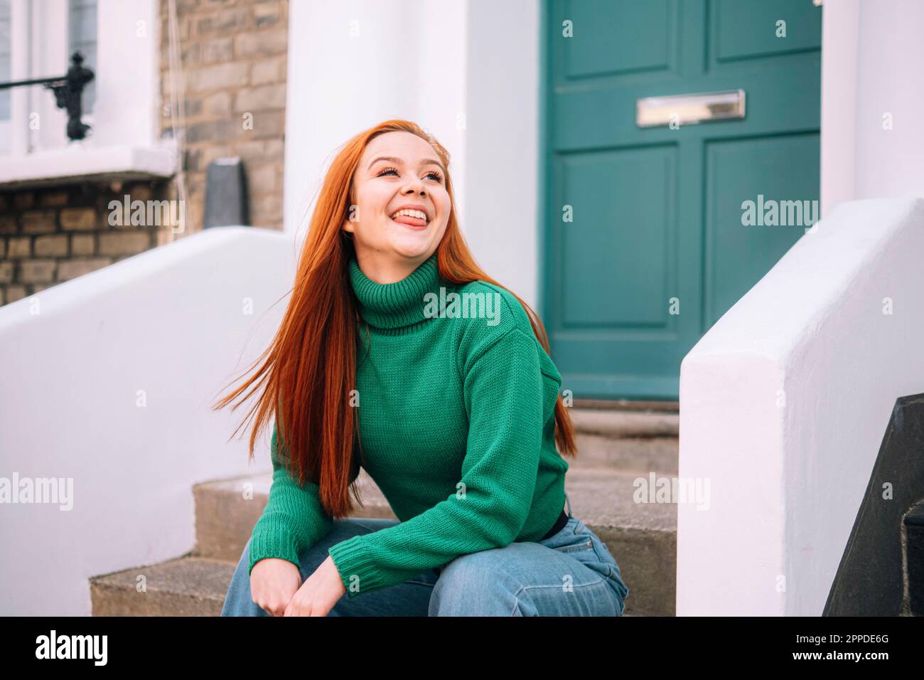 Giocosa donna rossa che esce lingua fuori casa Foto Stock
