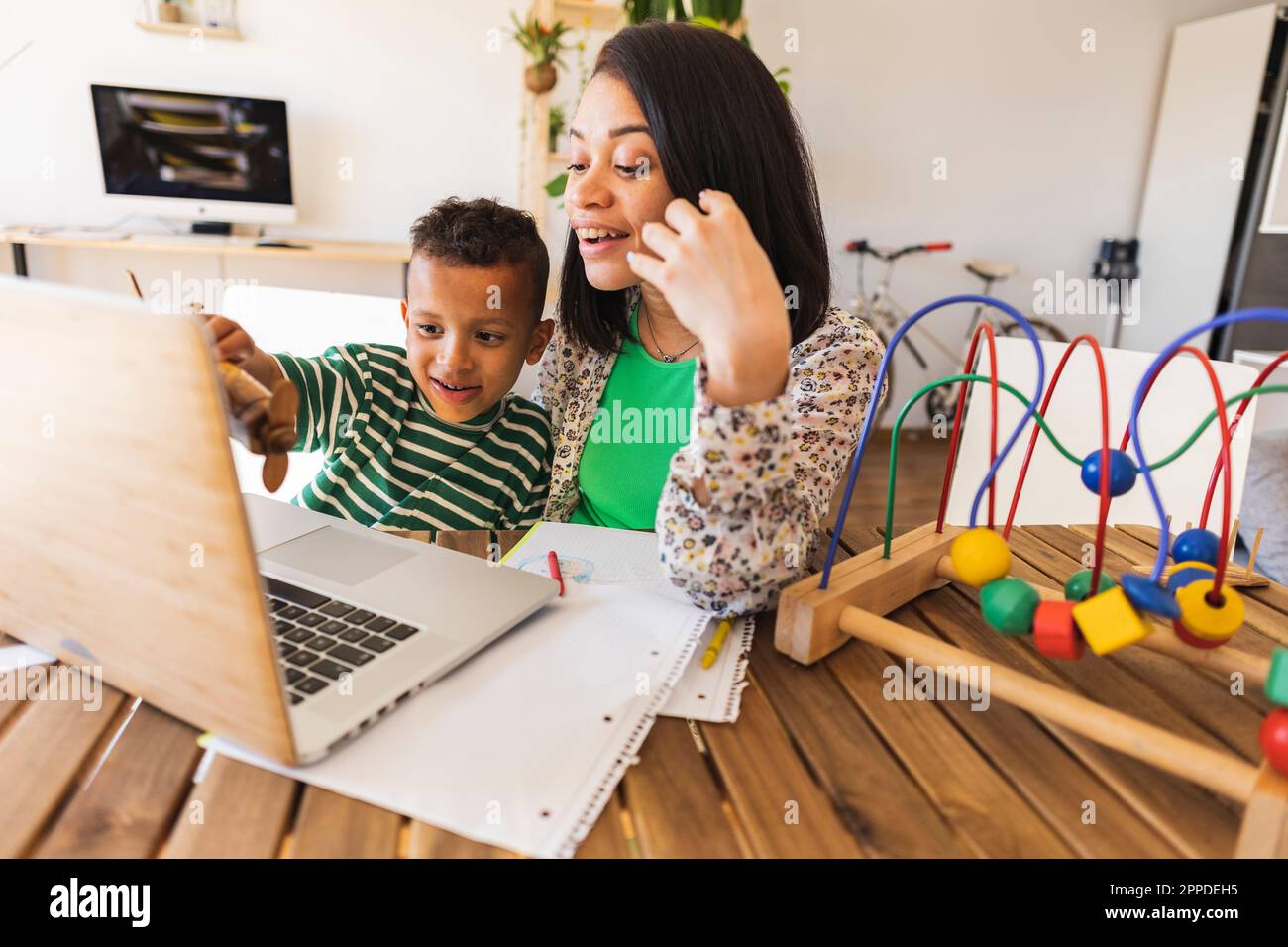 Madre felice che condivide il notebook con un figlio a casa Foto Stock