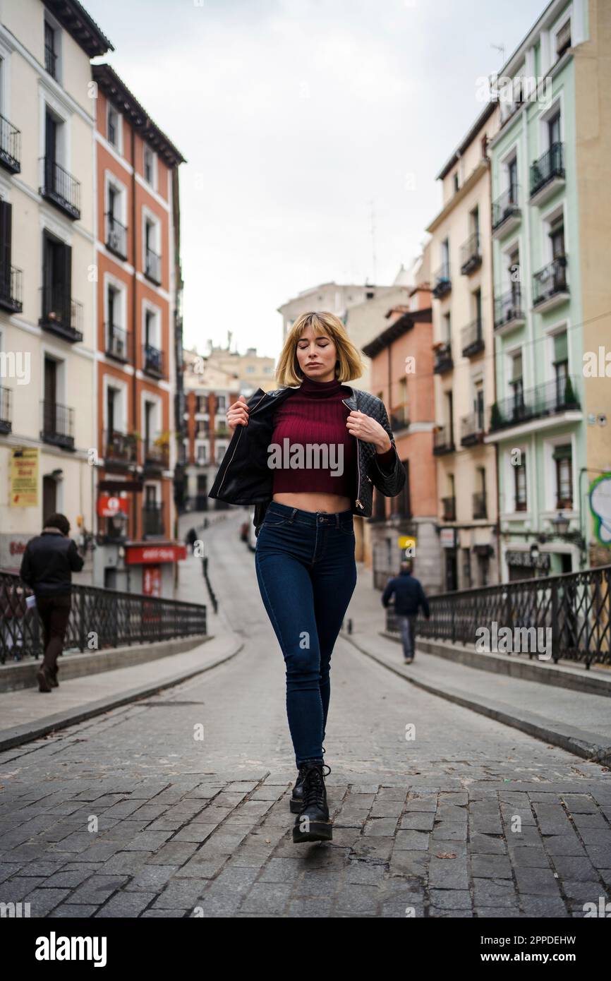 Donna che cammina per strada tra edifici in città Foto Stock