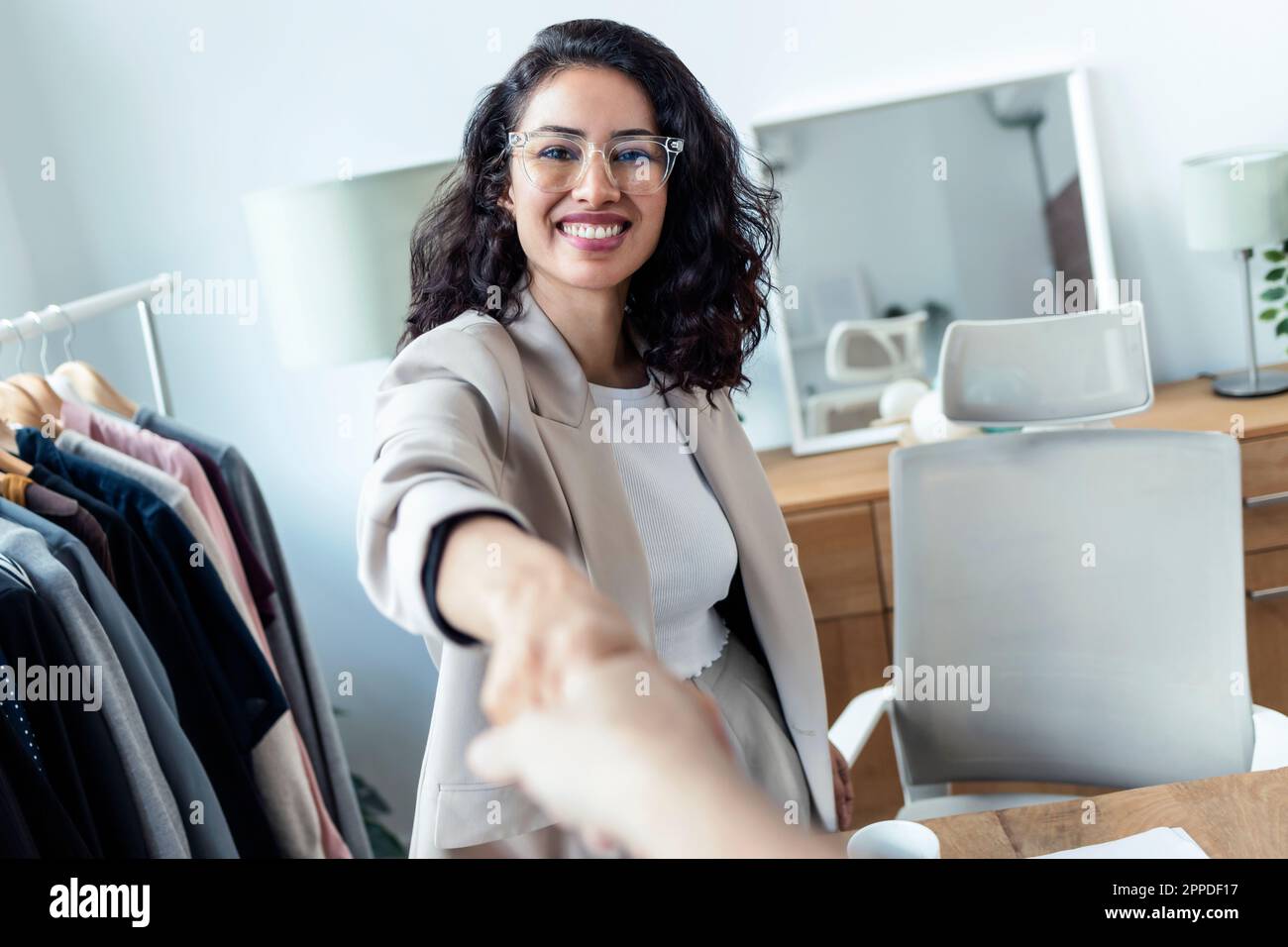 Felice stilista di moda che scuote la mano con il cliente in studio Foto Stock