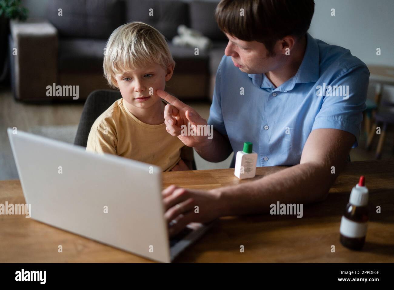 Padre che mostra la varicella del figlio al medico sul notebook a casa Foto Stock